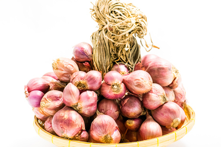 Fresh red shallot in bamboo basket isolated on a white background.の写真素材