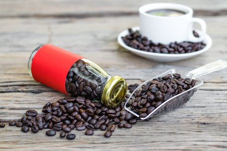 Roasted coffee beans in a red label glass bottle with a white cupの写真素材