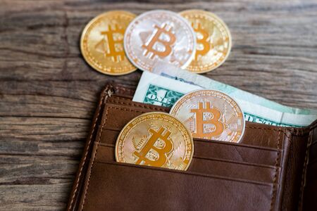 Bitcoin and leather wallet with one dollar bill on an old wood background.の写真素材
