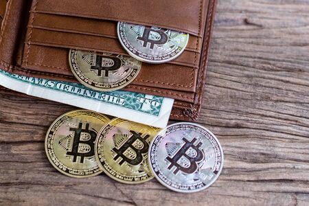 Bitcoin and leather wallet with one dollar bill on an old wood background.の写真素材