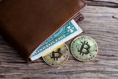 Bitcoin and leather wallet with one dollar bill on an old wood background.の写真素材