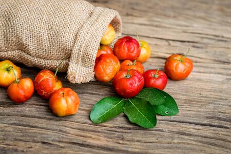 barbados cherry in hemp sacks on an old wooden tableの写真素材