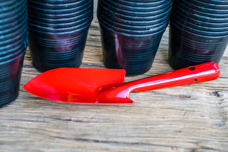 Garden tools shovel red with black planting pots on the old wooden
