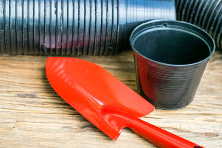 Garden tools shovel red with black planting pots on the old wooden
