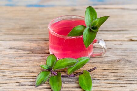 river spiderwort juice in a glass and river spiderwort leaf have medicinal properties on the old wooden tableの写真素材