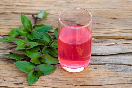 river spiderwort juice in a glass and river spiderwort leaf have medicinal properties on the old wooden tableの写真素材