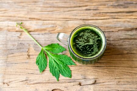 Herbal juice of white mugwort high medicinal benefits in a glass on an old wooden table.の写真素材