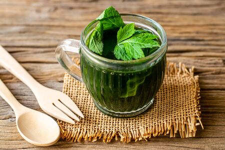 Herbal juice of white mugwort high medicinal benefits in a glass on an old wooden table.の写真素材
