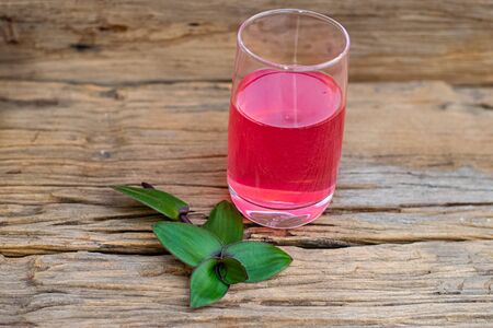river spiderwort juice in a glass and river spiderwort leaf have medicinal properties on the old wooden tableの写真素材