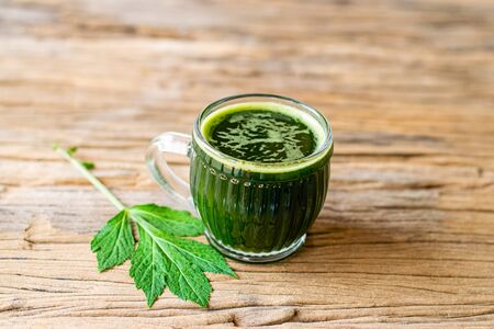 Herbal juice of white mugwort high medicinal benefits in a glass on an old wooden table.の写真素材