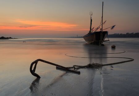 Fishing boat at the beach during sunsetの写真素材