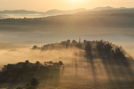 Landscape misty panorama. Fantastic dreamy sunrise on the mountains with view into misty valley below. Foggy clouds above forrest. View below to fairy landscape. Foggy forest hills.の写真素材
