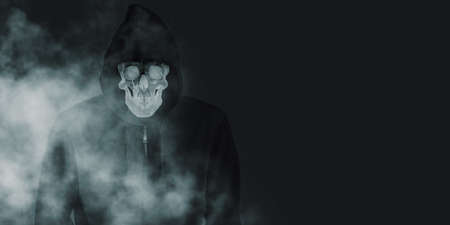 A devil skull in a black robe with a hood and a smoke skull smiling under a black shirt. The spirit in the coat Black background with smog 3d illustrationの写真素材