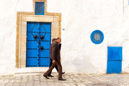SIDI BOU SAID, TUNISIA- APRIL 3: Two men walk in the medina in Sidi Bou Said, Tunisia on April 3, 2018のeditorial素材