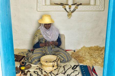 DJERBA, TUNISIA - APRIL 15: Woman shows how to make necklaces and crafts in a Museum in Djerba, Tunisia on April 15, 2018.のeditorial素材