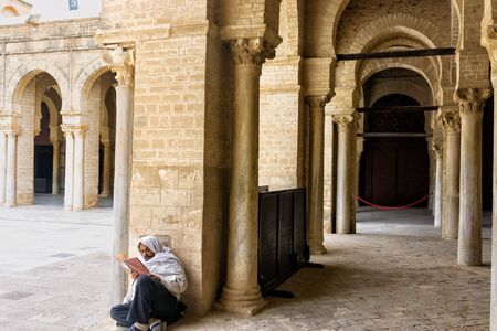 KAIROUAN, TUNISIA - APRIL 10: Inside view of Man reading the Quran in the courtyard of the Great Mosque in Kairouan, Tunisia on April 10, 2018.のeditorial素材
