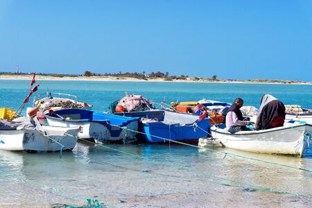 HOUMT SOUK, TUNISIA - APRIL 16: Two fishermen work on the shore of the Mediterranean sea in Djerba, Tunisia on April 16, 2018のeditorial素材