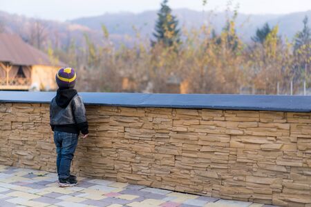 A child stands at the fence and looks away.A child stands at the fence and looks awayの写真素材