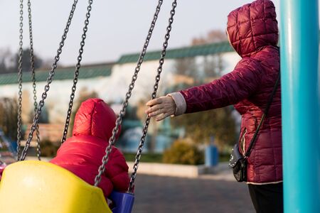 Grandmother shakes her grandson on a swing.Grandmother shakes her grandson on a swingの写真素材