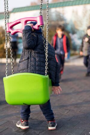 The child sits on a swing and wants to ride.The child sits on a swing and wants to rideの写真素材