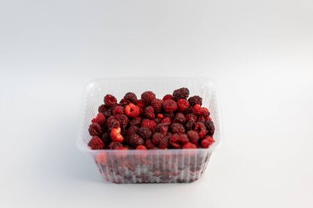 A lot of fresh raspberries in plastic packaging on a white background.A lot of fresh raspberries in plastic packaging on a white backgroundの写真素材