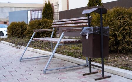Bench and trash can on the sidewalkの写真素材