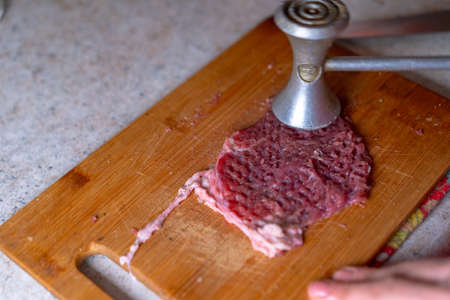 Beating a piece of meat for fryingの写真素材