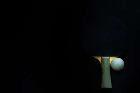 Tennis ball and table tennis racket on a black background
