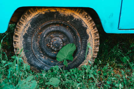 An old car with a rusty wheel stands on the grassの写真素材