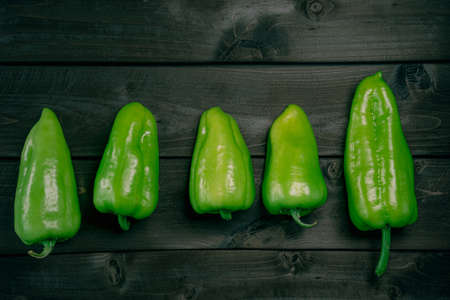 Green peppers on a wooden background