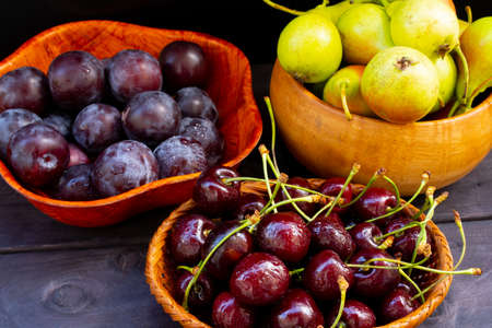 Plums, pears, cherries, on a wooden backgroundの写真素材