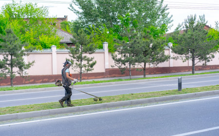 People in a protective mask mow the grass with a lawn mower.のeditorial素材