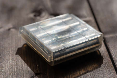 Storage container for aa batteries, on wooden background