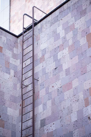 A ladder fixed to the building leads to the roofの写真素材