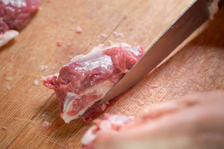 Cutting raw meat with a knife and handsの写真素材