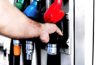 A man takes a hose from a car gas station.
