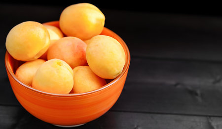 Ripe apricots in a bowl on a wooden backgroundの写真素材