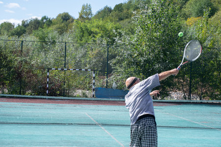 Aged man playing tennis on the courtの写真素材