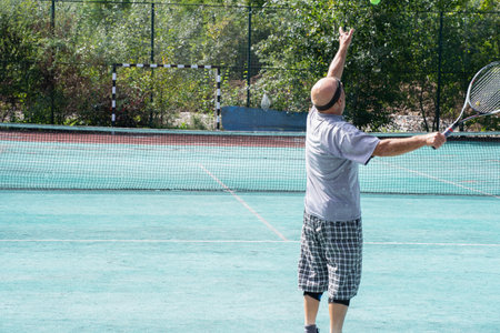 Aged man playing tennis on the courtの写真素材