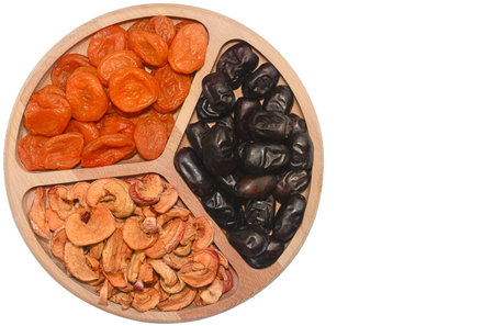 A wooden platter holds a variety of dried fruits including apricots, figs, and apples. The arrangement highlights the rich colors and textures, making it visually appealing.の写真素材