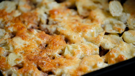 This delicious baked pasta features a melted cheese topping with a golden crust, served in a cozy kitchen setting. The dish highlights inviting aromas and a comforting vibe.の写真素材