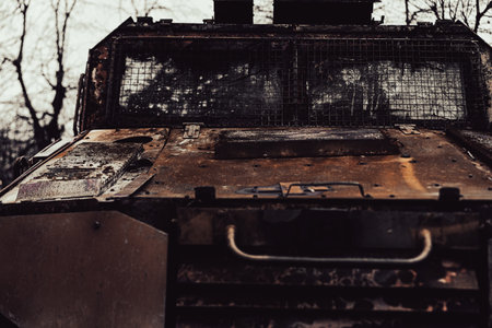 A rugged military vehicle stands alone among bare trees on a cloudy day. The weathered surface shows signs of wear, hinting at its storied past in various conflicts, now overtaken by nature.の写真素材