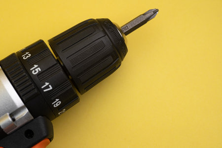 A detailed close-up of a cordless drill highlighting its chuck and screwdriver bit, with a vibrant...