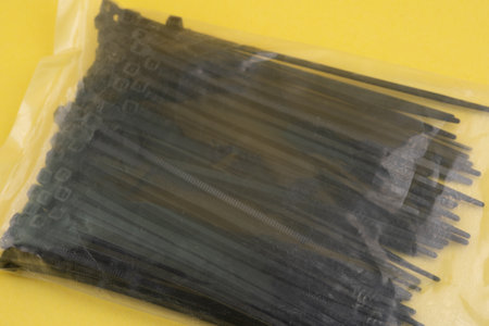 A packet of black cable ties is neatly packaged and ready for use. These ties are ideal for organizing cables, fastening items, and DIY projects. Perfect for home and office organization.の写真素材