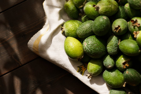 A collection of ripe feijoas is arranged on a light cloth, showing the vibrant green color in soft daylight. This display highlights the essence of autumn harvest.の写真素材