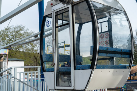 Visitors prepare to board the cable car at the amusement park, enjoying panoramic views of the surrounding greenery and attractions on a pleasant day.の写真素材