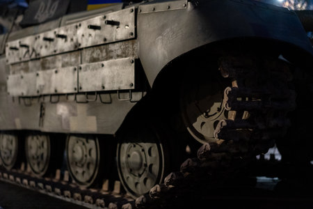 A military tank is prominently displayed in a dark exhibition space, highlighting its armored design and detailed structure. Visitors admire its historical significance and engineering.の写真素材