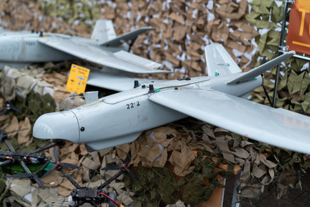 The display features a military drone positioned prominently among camouflage netting, highlighting its advanced design. The exhibition setting emphasizes technological innovation in defense.の写真素材
