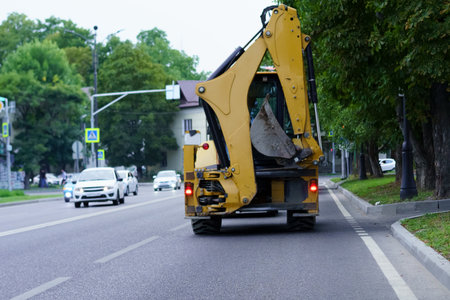 A large construction vehicle is positioned on the side of a busy road, preparing for street repairs....