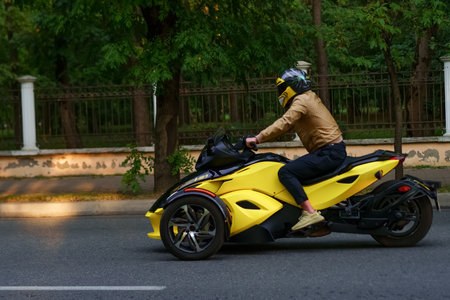 A rider is enjoying a ride on a striking black and yellow motorcycle on an urban street. The early...